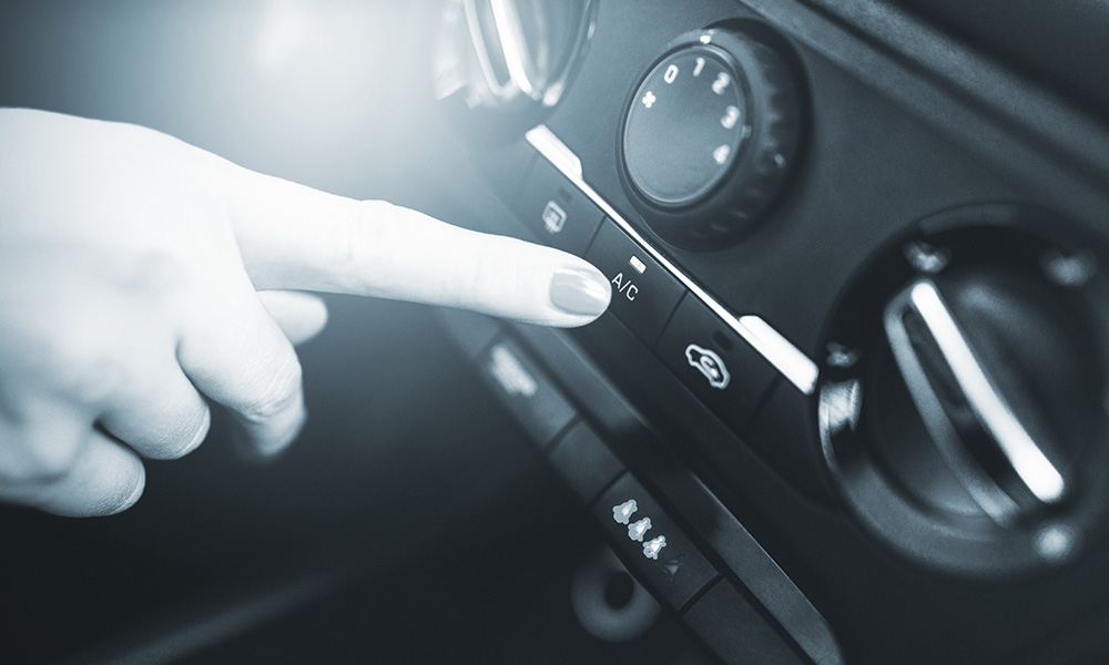 Photo of a women pointing to the A/C button on a vehicle